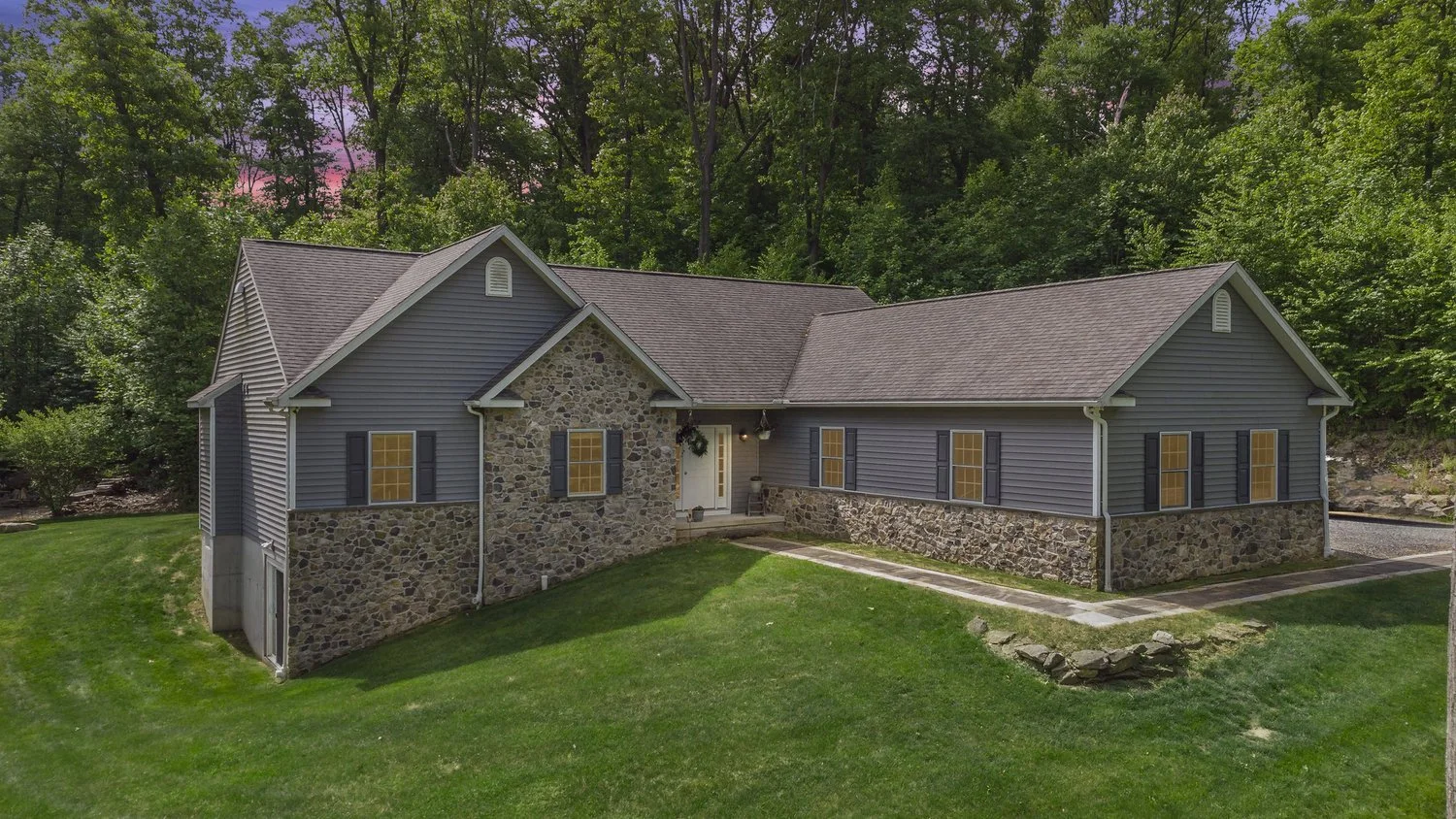 Aerial view of a stone-front home surrounded by trees